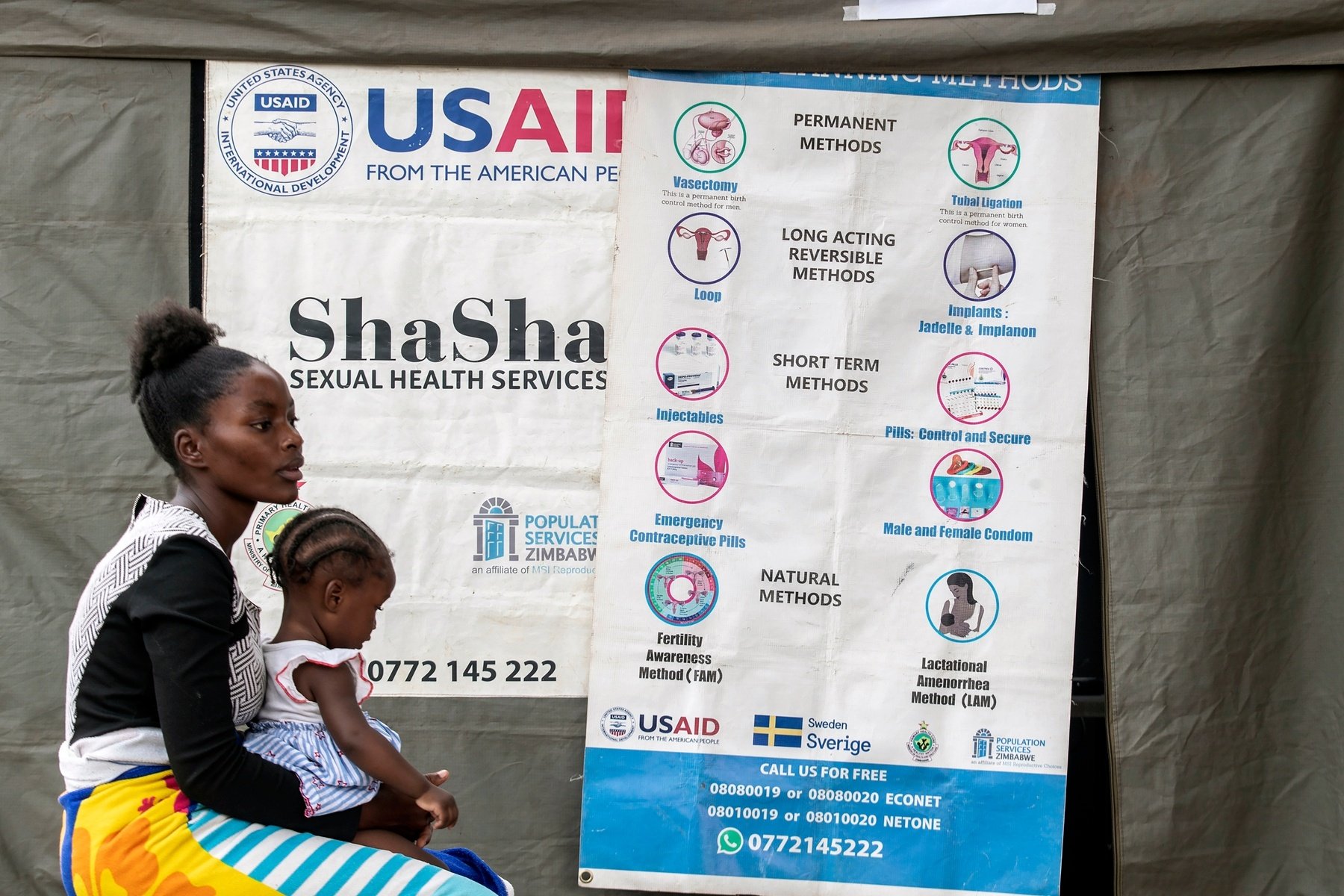 A woman sits with a child at a health care clinic.