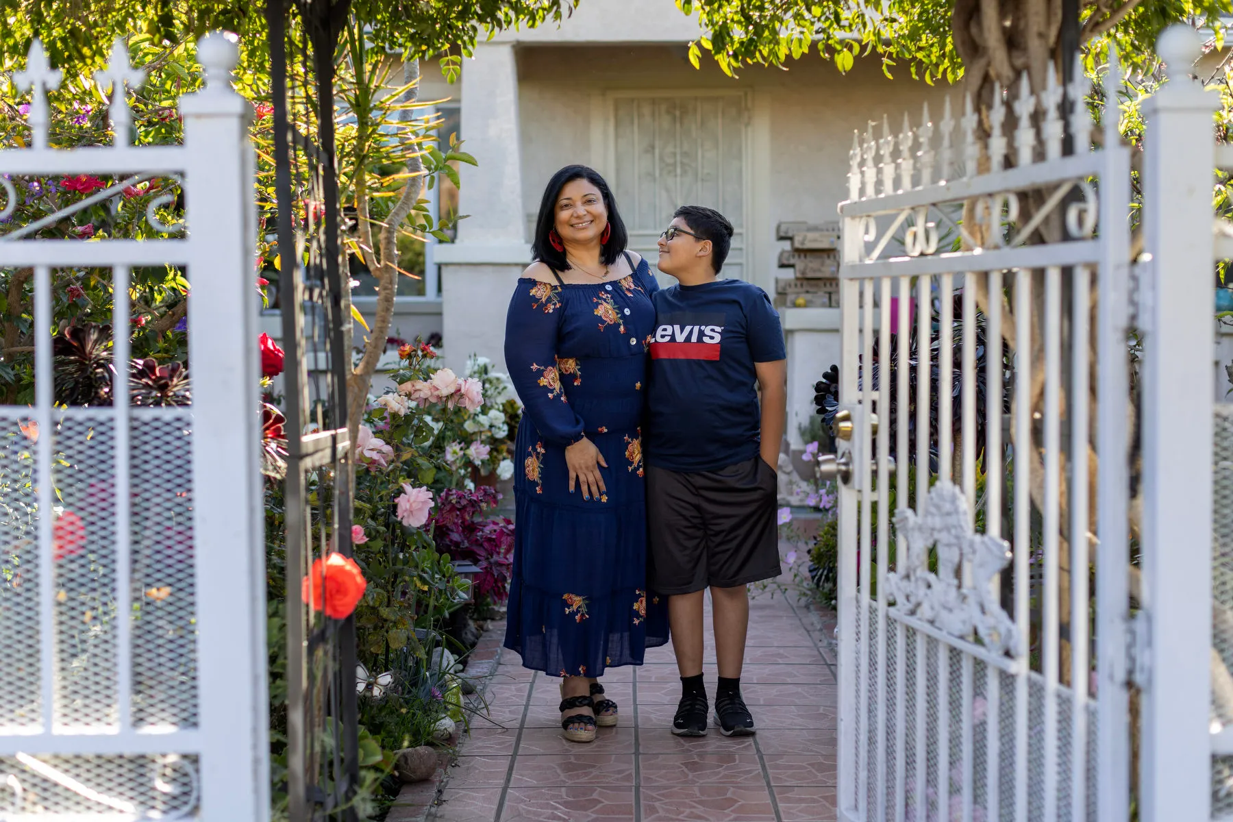 A woman smiles beside her son as he looks up at her.