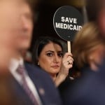 A woman holds a sign saying 