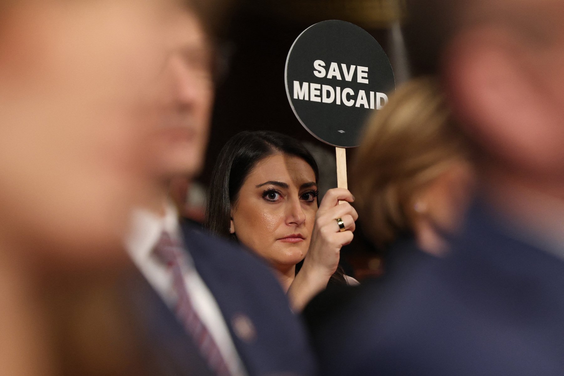 A woman holds a sign saying "save medicaid."