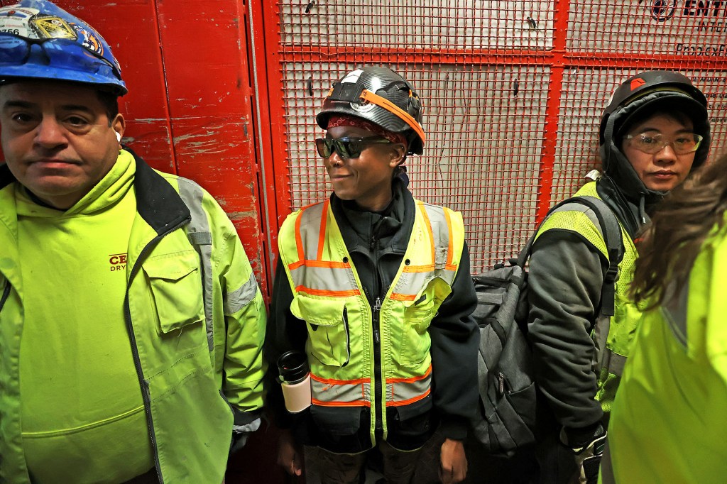 Women in construction ride a service elevator in Boston.