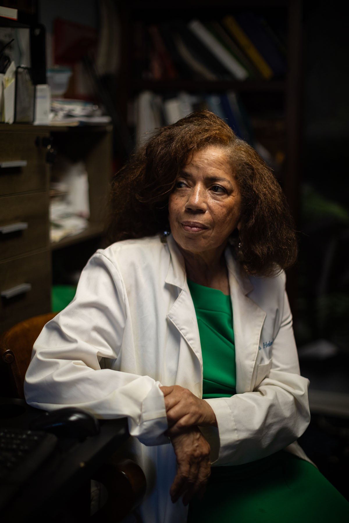 Dr. Helen Jackson, wearing a lab coat, poses for a portrait in her home office.