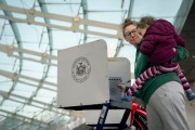 A women holds her daughter as she fills out her ballot at a polling site.