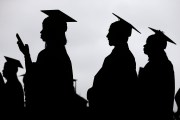Graduates in graduation gowns shown in silhouette.