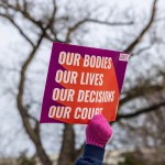 A gloved hand holds a pro-choice protest sign.
