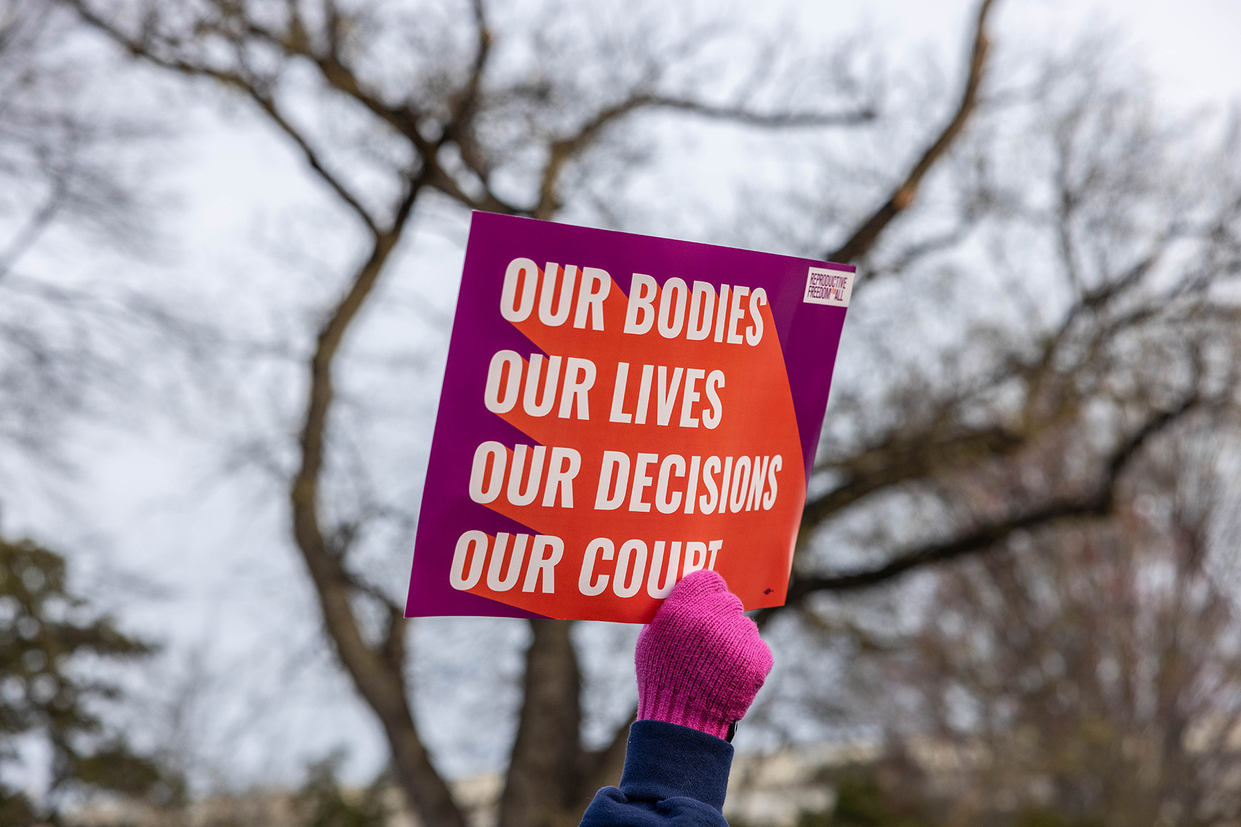 A gloved hand holds a pro-choice protest sign.