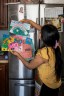 Ruano places her daughters’ colorful drawings on the refrigerator.