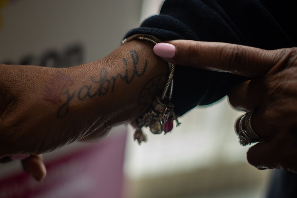 A woman points at a tattoo on her arm.