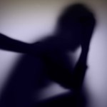 A blurred, shadowy silhouette of a person holding their head in one hand.