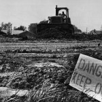 A bulldozer moves dirt at Love Canal in May 1980, with a “Danger Keep Out” sign posted in the foreground during early cleanup efforts.