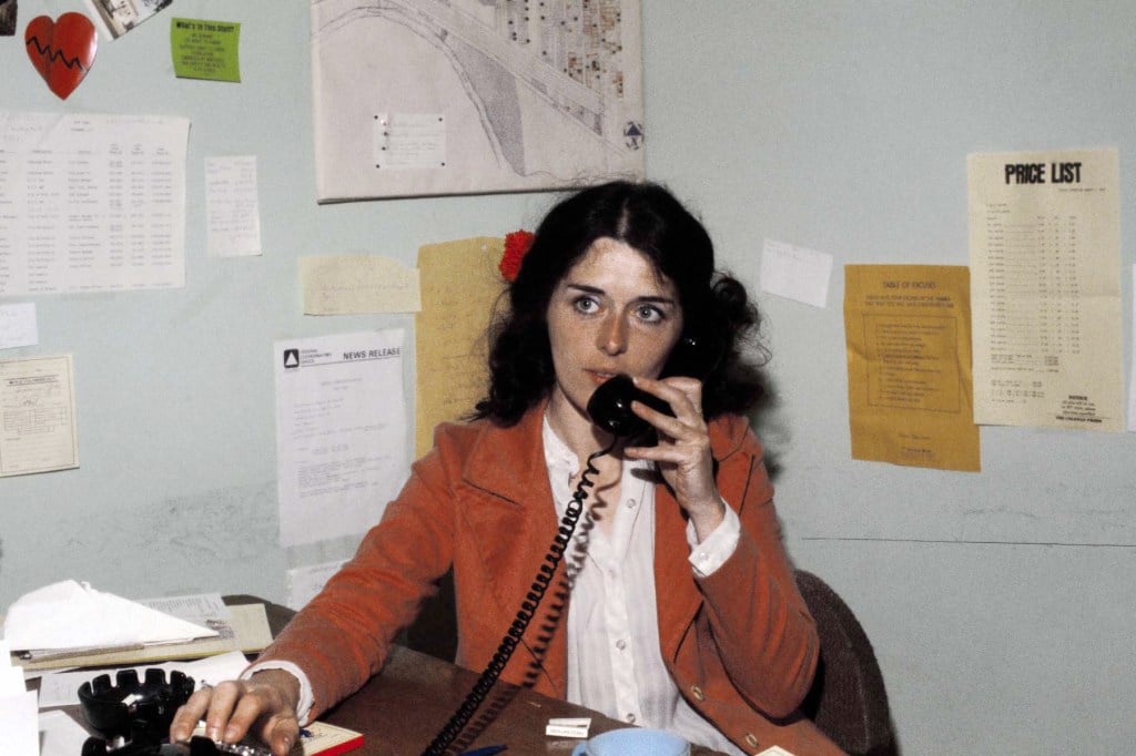 Lois Gibbs, president of the Love Canal Homeowners Association, speaks on the phone at a desk covered in papers and maps.