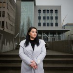 A woman stands at the steps of a courthouse.