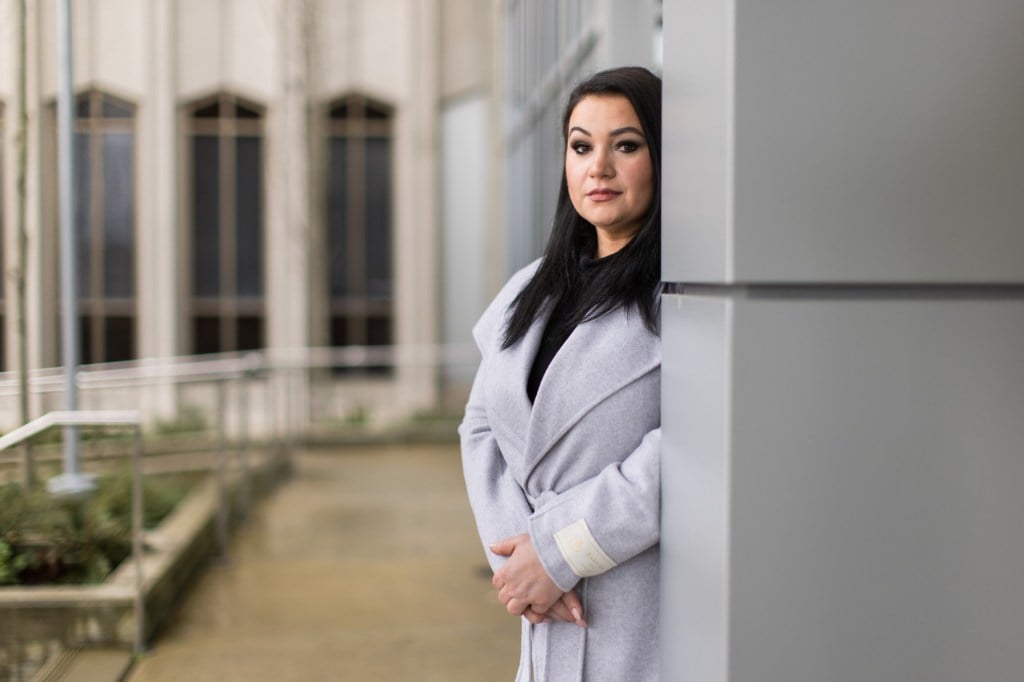 A portrait of a woman near a courthouse building.