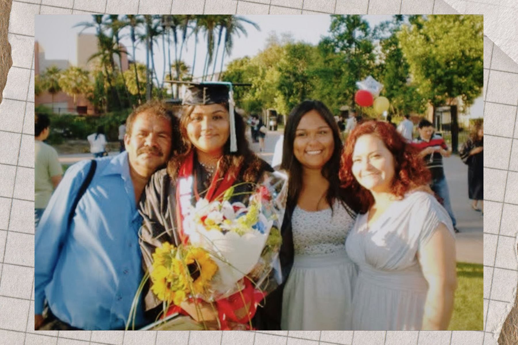 Reyes wears a cap and gown, holding flowers and standing with three smiling family members on graduation day.