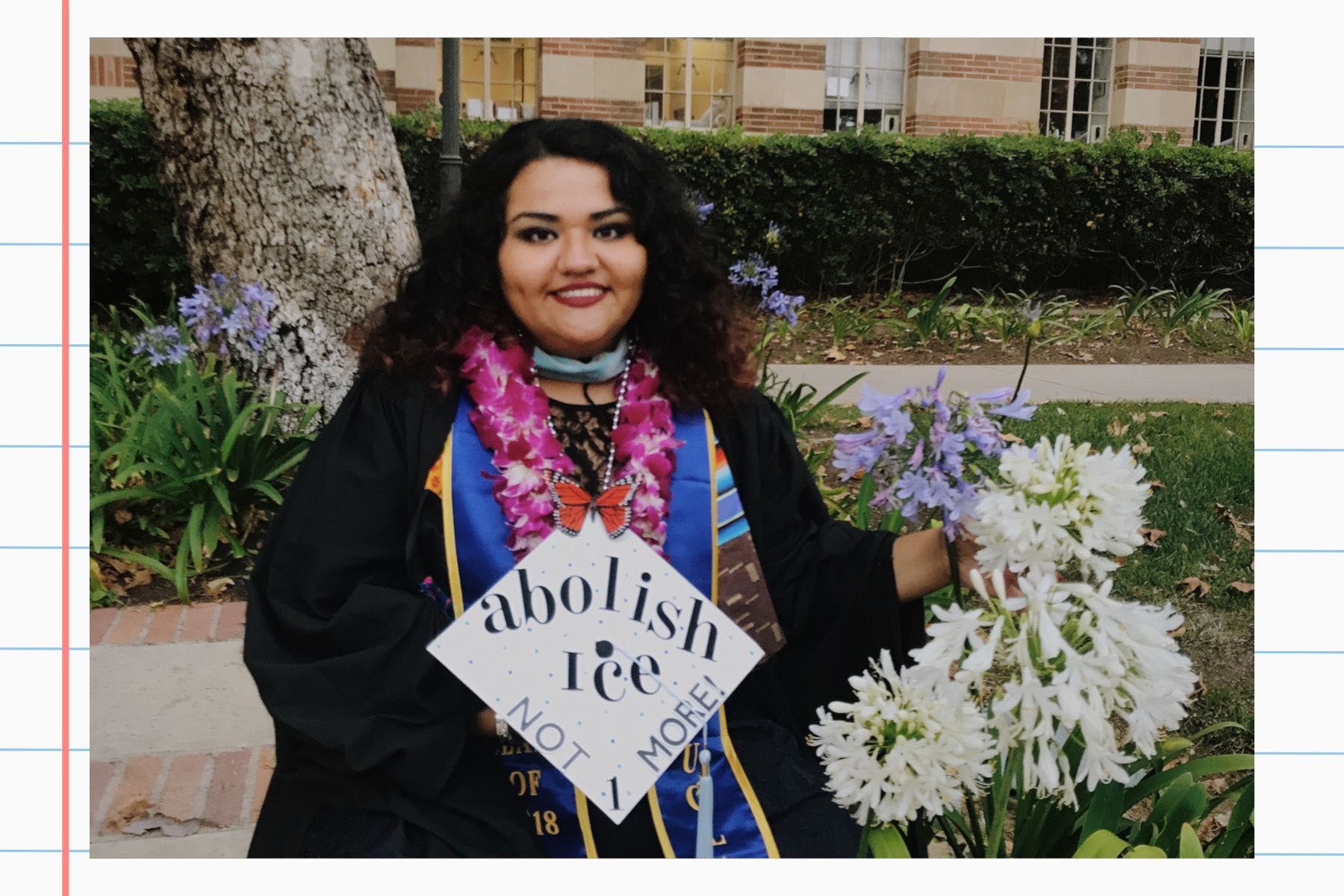 Reyes smiles in her graduation gown, holding flowers and wearing a decorated cap that reads “abolish ICE — not 1 more!”