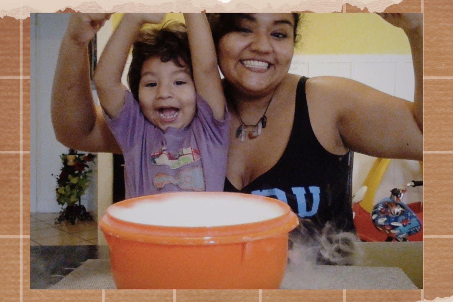 A younger Reyes and her son Nathan smile and throw their arms up while seated at a table with a bubbling orange bowl.