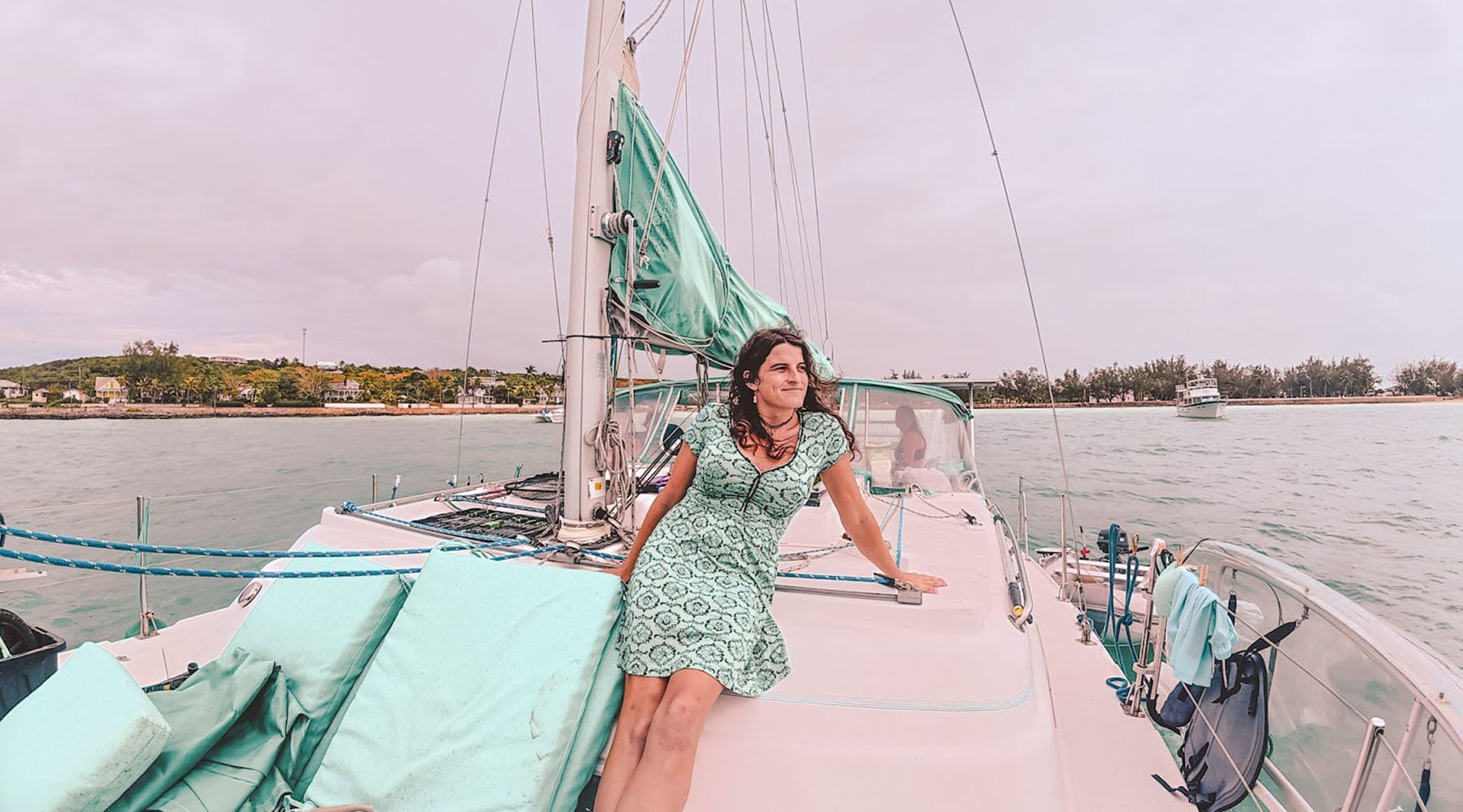 Kelsey Granger in a mint green patterned dress relaxes on the deck of a sailboat