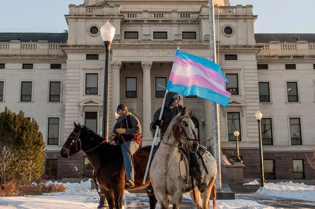 Two protestors on horseback in front of the South Dakota capitol building.
