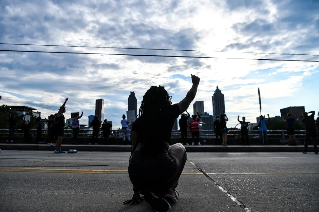 A protestors raises a fist in the sky against the Atlanta skyline
