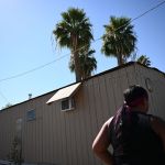A woman walks toward an air conditioning unit near a trailer.