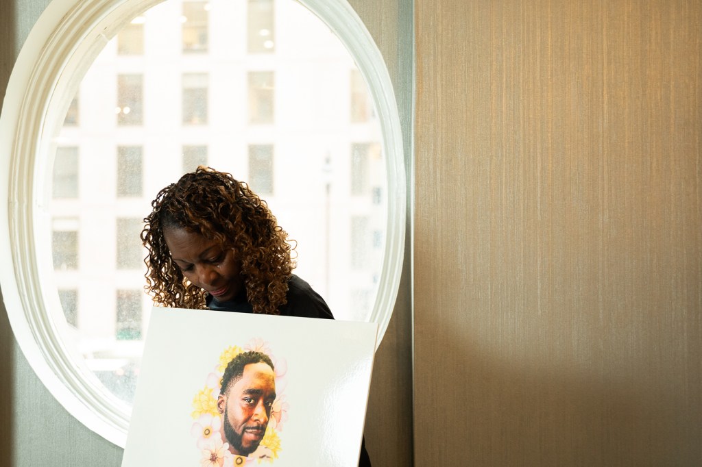 A woman holds a poster depicting her late son.