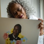 A woman lays her head on a poster depicting her late son.