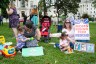 Mothers with young children sit on the grass outside the U.S. Capitol protesting cuts to Medicaid.