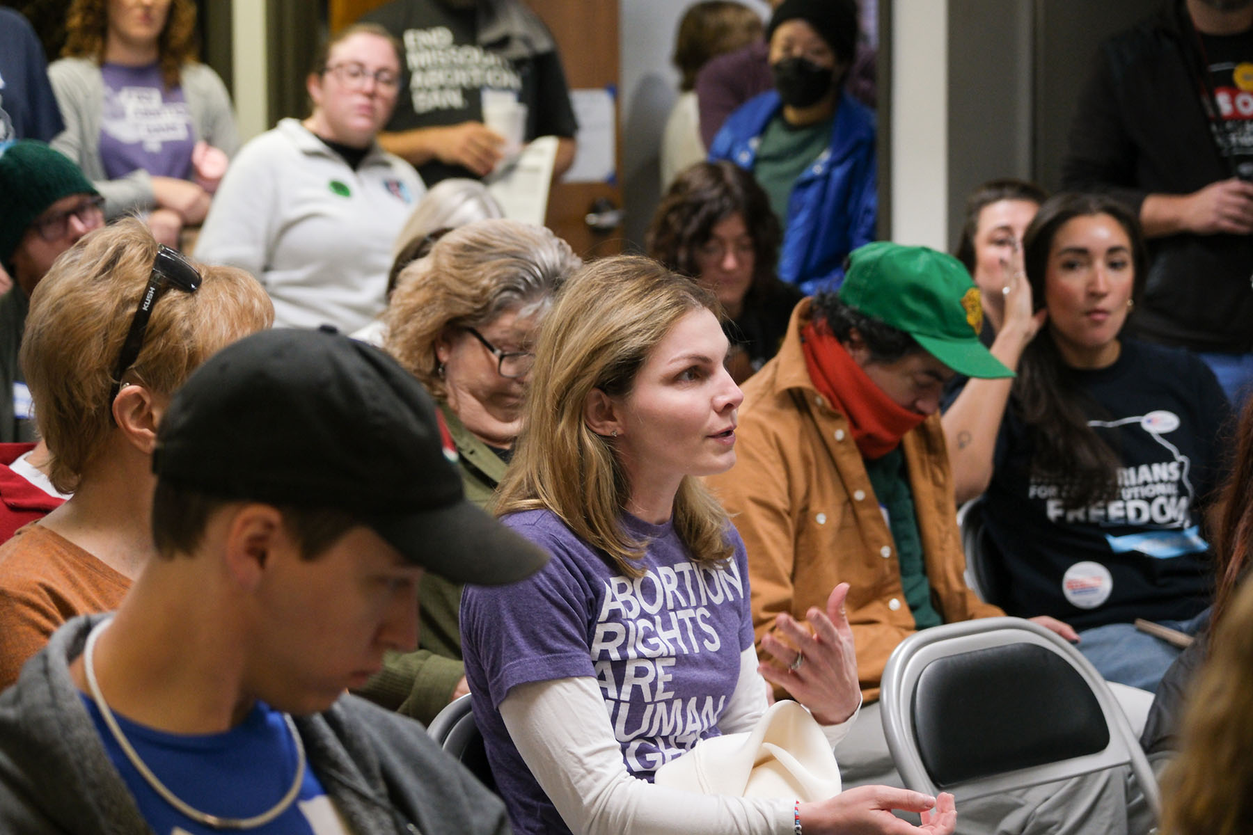 A doctor wearing a purple “Abortion rights are human rights” shirt addresses a crowd at a canvassing meeting in Kansas City.