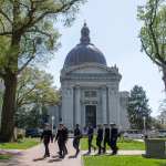A line of naval academy students walk on the campus.