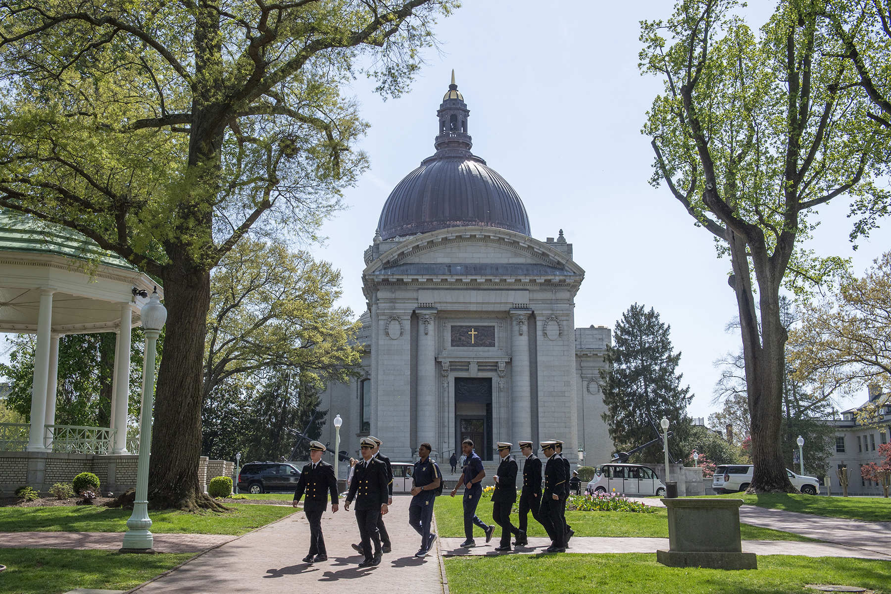 A line of naval academy students walk on the campus.