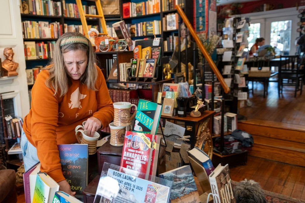 A woman arranges books in a display at a book store.