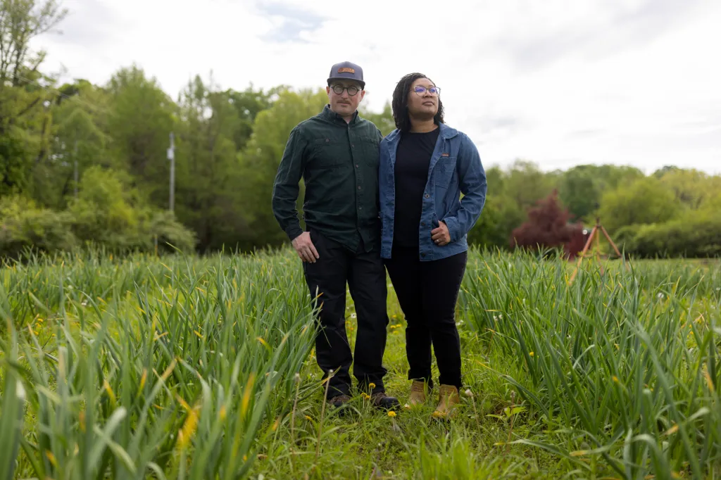 Two people stand for a portrait on their farm.