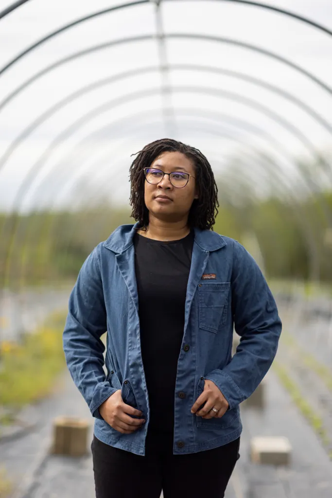 A woman farmer stands in her greenhouse.