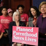 U.S. Sen. Tammy Baldwin speaks in front of a podium at a news conference.