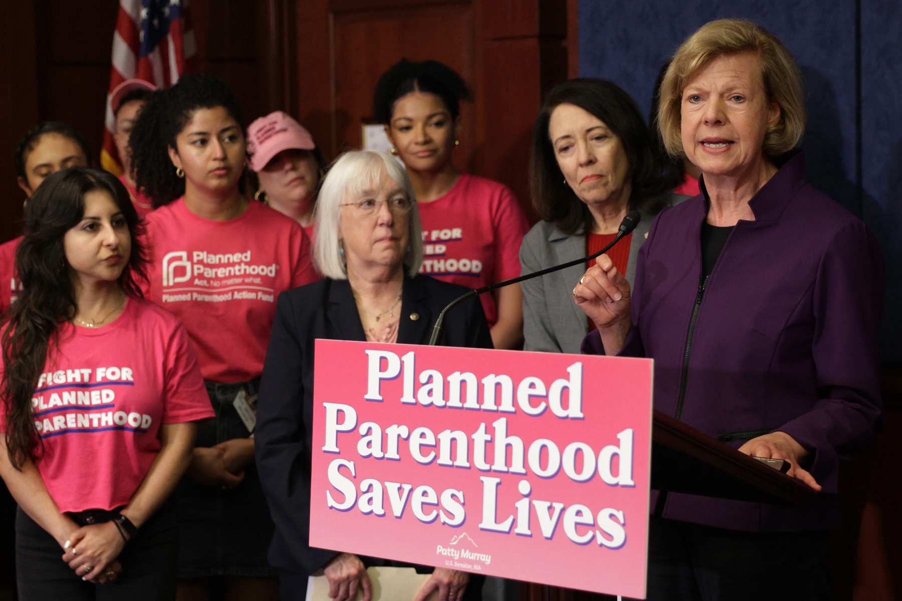 U.S. Sen. Tammy Baldwin speaks in front of a podium at a news conference.