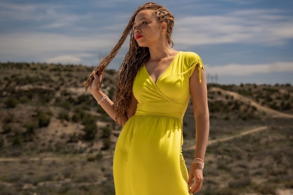 Um retrato de uma mulher contra um cenário de paisagem árido.