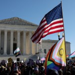 A crowd waves transgender and LGTBQ+ flags in front of the Supreme Court.