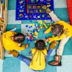 Three little kids play in a circle in a day care center.