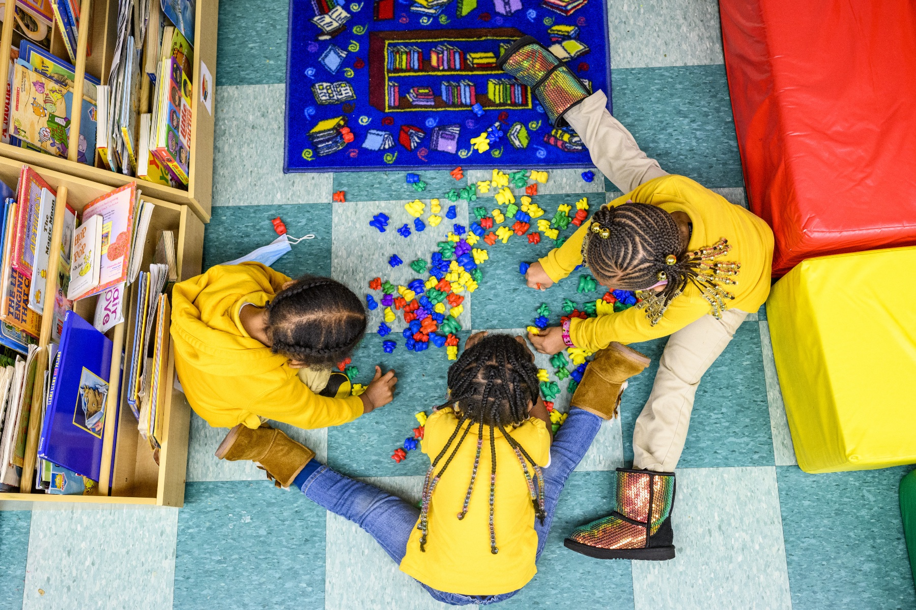 Three little kids play in a circle in a day care center.