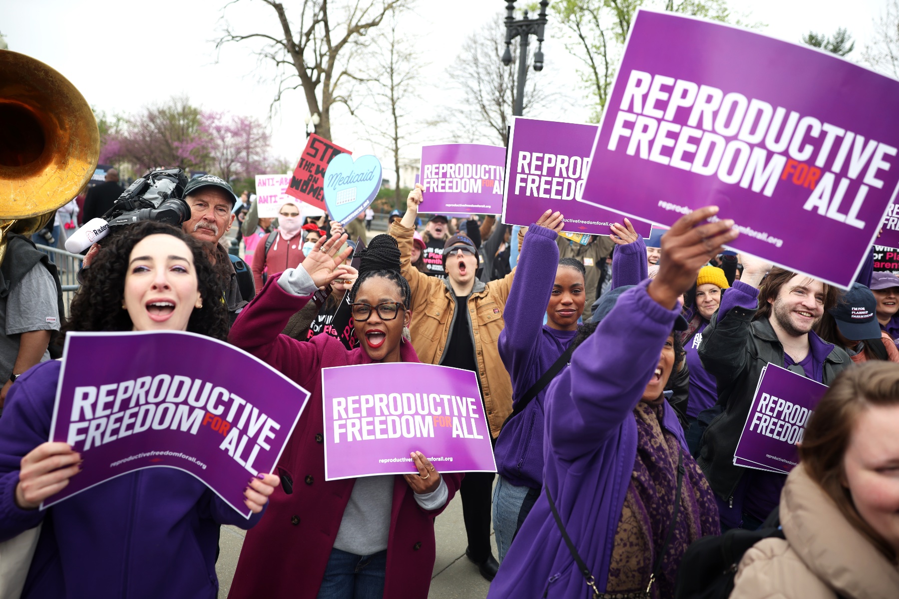 Protesters holding signs that read "reproductive freedom for all."