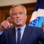 Health and Human Services Secretary Robert F. Kennedy Jr. speaks while pointing his finger wearing a blue suit with stripes on it.