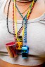 A necklace made of rainbow beads, a whistle, shot glass and a popper bottle.