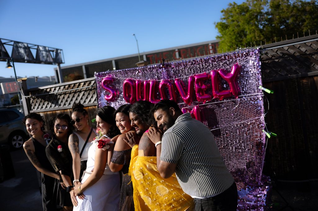 A group of people hold onto each other in front of a sign saying Soulovely.