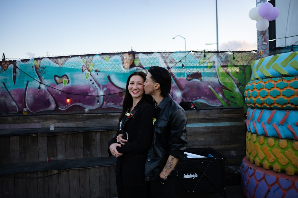 A couple holds each other close and one kisses the cheek of the other.