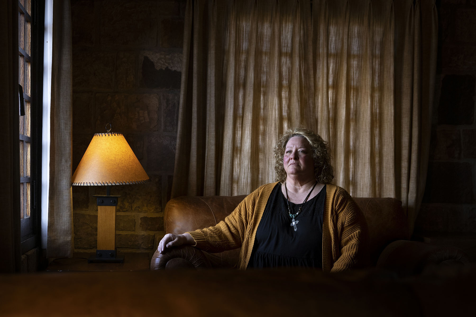 Cheryl Thompson sits on a couch as she poses for a portrait near her home.