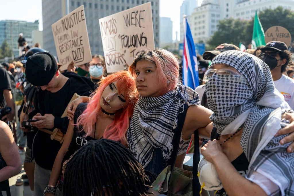 Os manifestantes se mantêm enquanto as pessoas enfrentam a Guarda Nacional da Califórnia e a polícia fora de um prédio federal em Los Angeles.