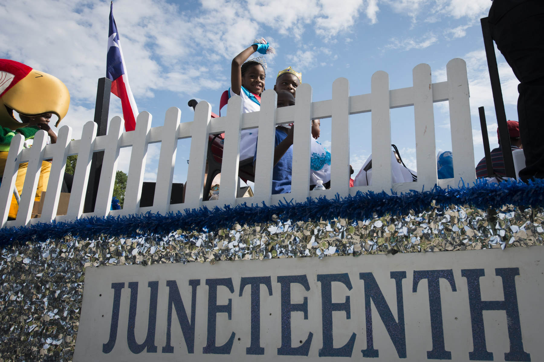 Children wave from a float that says Juneteenth.