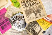 A display of archival photos, fliers and newspapers spread out.