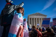 A child looks out at the crowd during a protest in support of care for transgender youth outside the Supreme Court during the United States v. Skrmetti arguments.