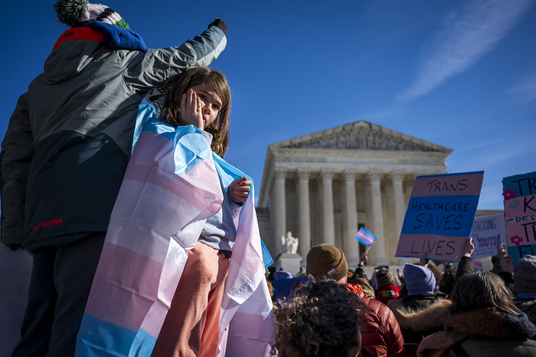 A child looks out at the crowd during a protest in support of care for transgender youth outside the Supreme Court during the United States v. Skrmetti arguments.